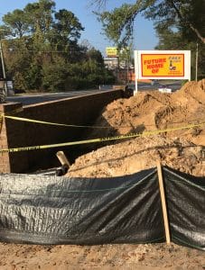 A large hole being dug on the side of the road in compliance with the Stormwater Training Center's Construction SWPPP certifications