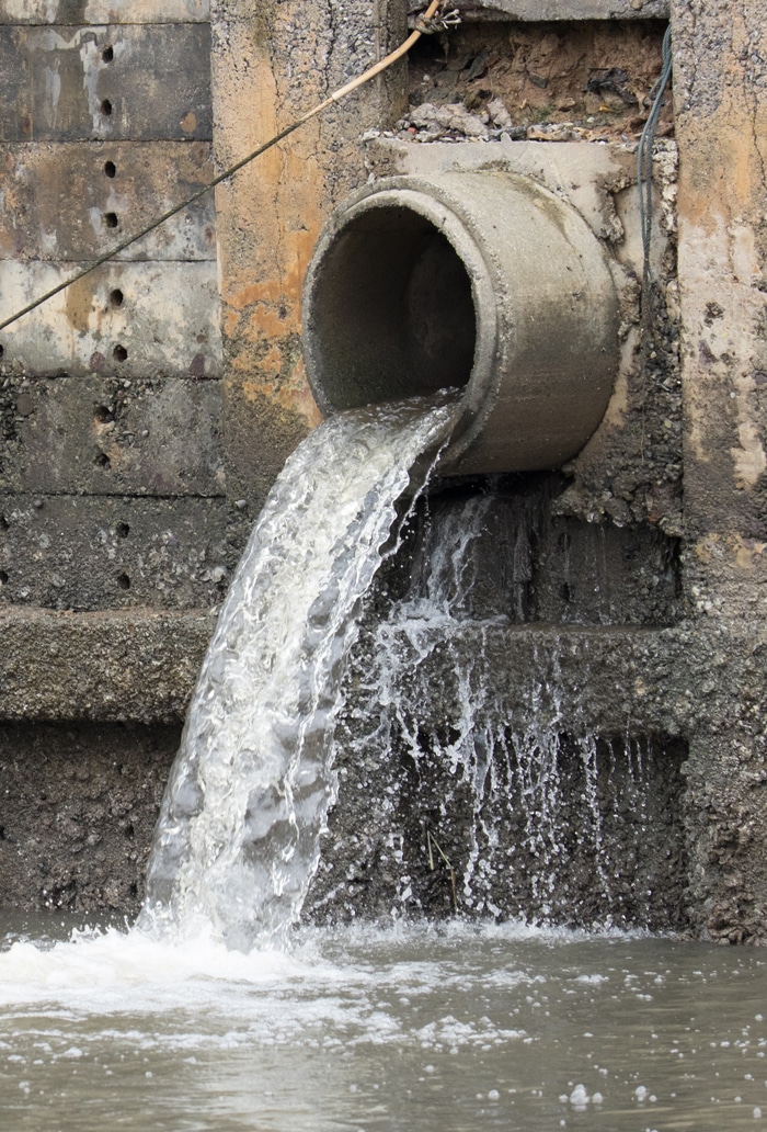 Large cement pipe draining storm water into a body of water